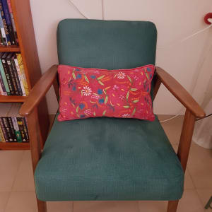 כרית צבעונית על כורסה ירוקה עם ריפוד עץ