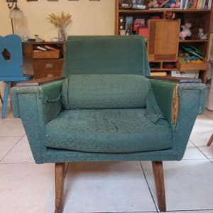 כורסה ירוקה עם ריפוד קרוע בצדדים