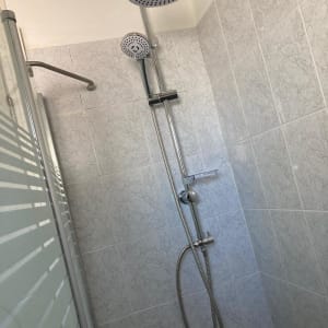 ראש מקלחת כפול עם צינור מתכת על קיר אריחים