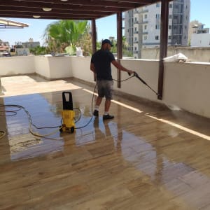 אדם מנקה רצפה עם מכונת שטיפה בלחץ מים