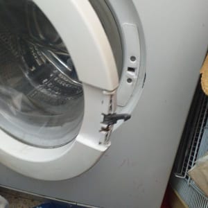 מכונת כביסה עם דלת שבורה ותוף פנימי