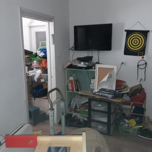 חדר מבולגן עם מדפים עמוסים, טלוויזיה וקופסאות אחסון