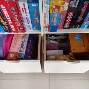 משחקי קופסה מסודרים על מדף ומגירות פתוחות עם צעצועים