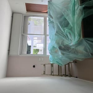 סולם וחפצים מכוסים בניילון ירוק בחדר צבוע