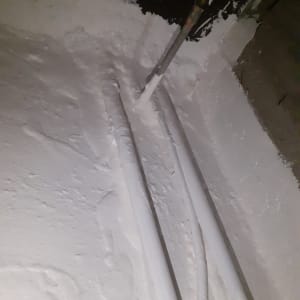 צינורות מכוסים בחומר איטום לבן על רצפה