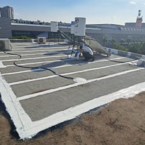 אדם מורח חומר איטום על גג עם מברשת