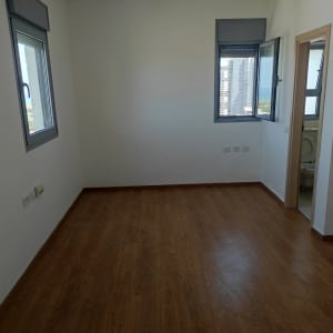 חדר ריק עם רצפת עץ וקירות לבנים