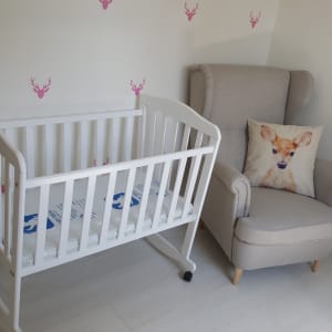 עריסה לבנה עם גלגלים על רצפת עץ בהירה