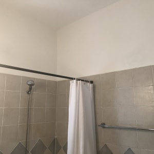 קיר צבוע בלבן מעל אריחי קרמיקה במקלחת