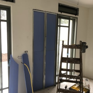 לוחות גבס כחולים ליד חלון עם סולם וכלי עבודה