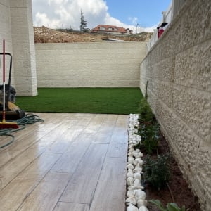 צינור השקיה, אבנים לבנות, צמחים באדמה, דשא סינתטי