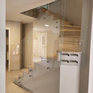 מעקה זכוכית שקוף עם מחברים מתכתיים במדרגות