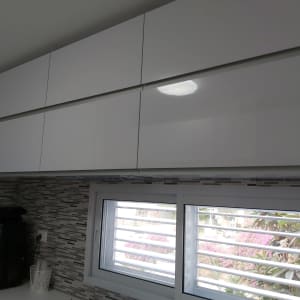 ארונות מטבח לבנים מעל חלון עם תריסים