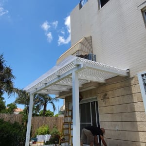 התקנת פרגולה לבנה בגינה עם כלים וסולם