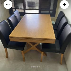 שולחן עץ עם כיסאות מרופדים שחורים סביבו