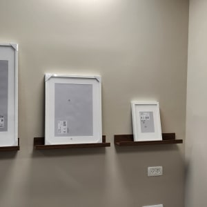 מסגרות תמונה על מדפים מעץ על קיר