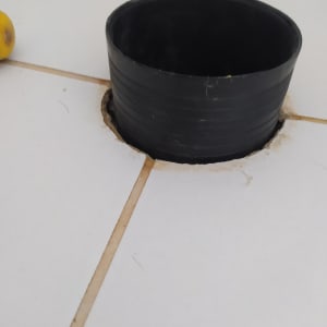 צינור שחור עגול בתוך חור ברצפה לבנה