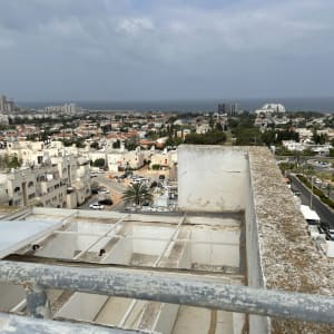 גג עם מעקה מתכת ומבנה בטון