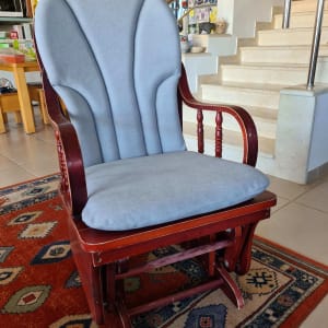 כיסא נדנדה עם ריפוד אפור על שטיח צבעוני