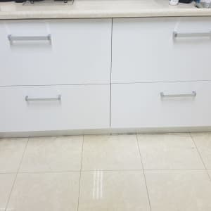 ארונות מטבח לבנים עם ידיות מתכת על רצפת קרמיקה