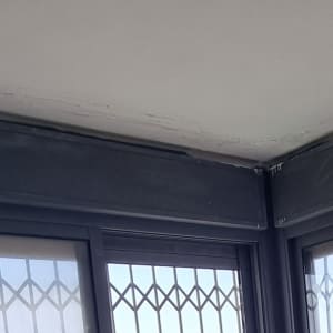 תקרה עם סימני רטיבות ליד חלון עם סורגים