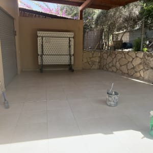 דלי עם מברשת וחומר איטום על רצפה מרוצפת