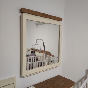 מראה תלויה על קיר מעל שידה מעץ