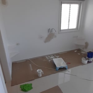 חדר עם קירות צבועים, כלי עבודה וצבע על הרצפה