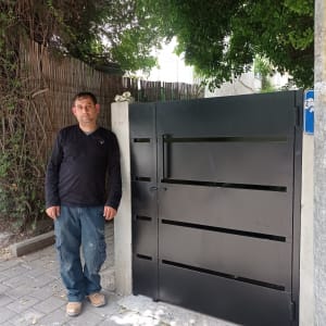 שער מתכת שחור עם מסגרת עבה ליד עמוד בטון