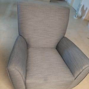 כורסה מרופדת בבד אפור עם משענות רחבות