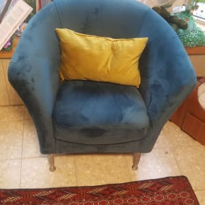 כורסה כחולה עם כרית צהובה על מושב