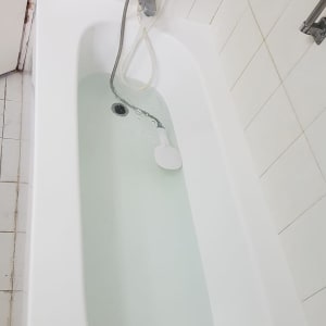 אמבטיה לבנה עם מים וברז מקלחת