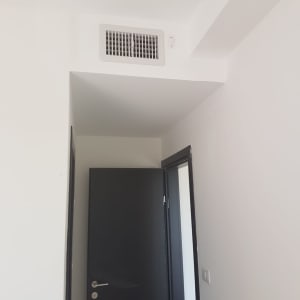 פתח אוורור של מזגן בתקרה לבנה