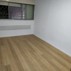 רצפת פרקט עץ בחדר ריק עם קיר לבן