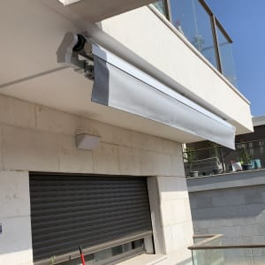 סוכך אפור מותקן על קיר חיצוני של מרפסת