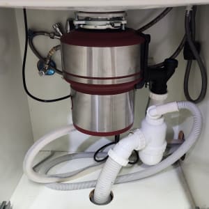 מתקן טוחן אשפה מתחת לכיור עם צינורות חיבור