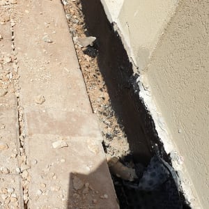 איטום קיר חיצוני עם חומר שחור ליד חלון