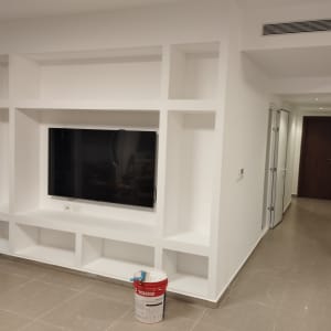 קיר גבס עם טלוויזיה ודלי צבע על הרצפה