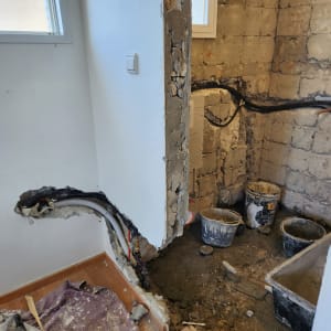 שיפוץ קיר עם צינורות חשופים ודליים על הרצפה