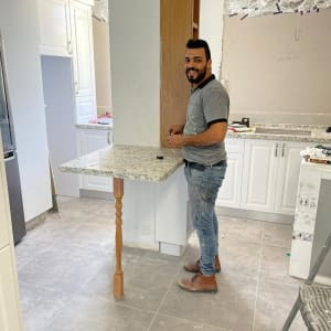 אדם עובד במטבח עם משטח שיש וכלי עבודה