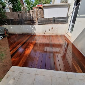 דק עץ חדש בגינה עם אדם עובד בצד