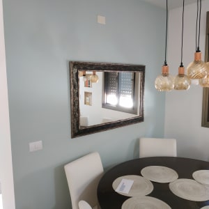 קיר צבוע בצבע תכלת עם מראה במסגרת כהה