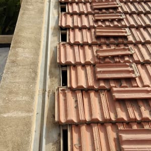 רעפים חומים על גג עם פתחים בין השורות