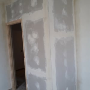 קיר גבס עם חיבורים מטויחים ליד דלת עץ