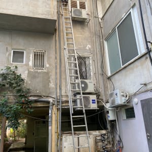 אדם על סולם ליד צינורות ומזגנים