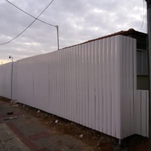 גדר לבנה גבוהה עשויה מלוחות עץ אנכיים