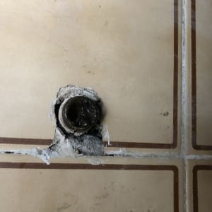 צינור מים חשוף ברצפה עם אריחים