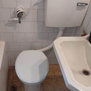 אסלה, מיכל הדחה, כיור וצינור מים בחדר אמבטיה