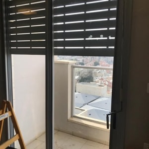 תריסים אפורים על חלון זכוכית במרפסת