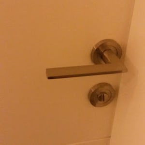 ידית דלת מתכתית על דלת לבנה